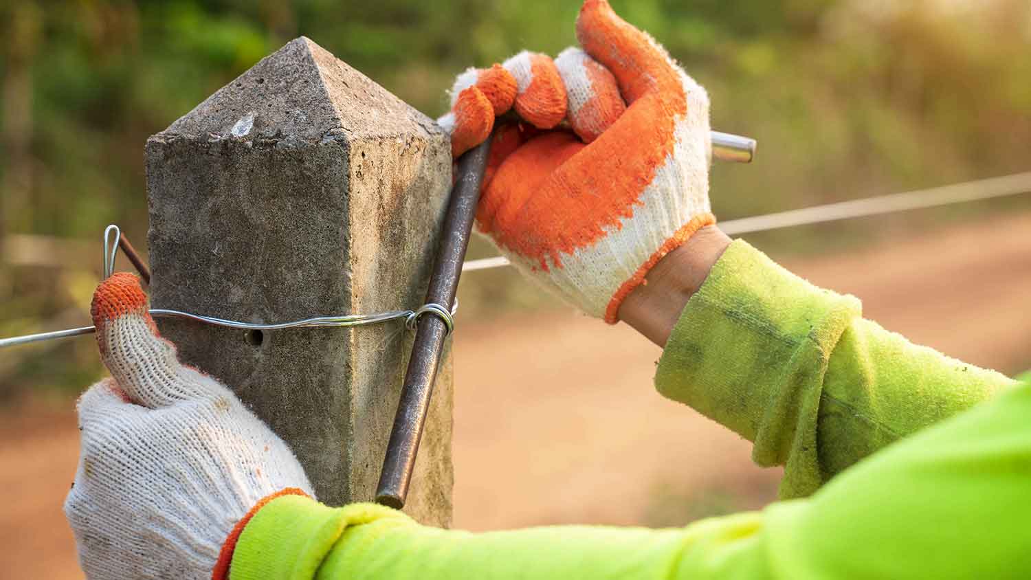 Closeup of a farmer installing an straining line wire fence