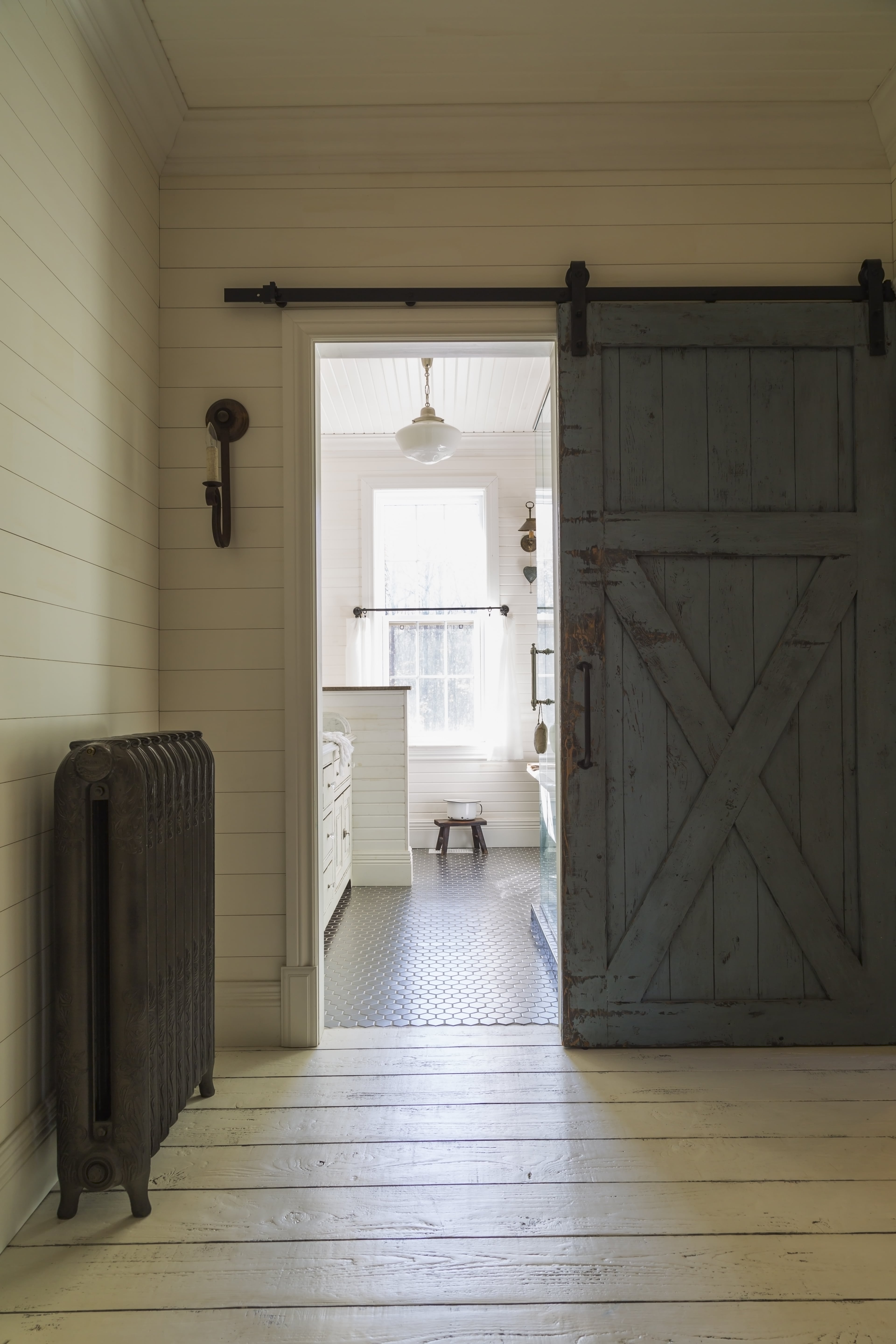 A rustic barn door leading into a farmhouse bathroom