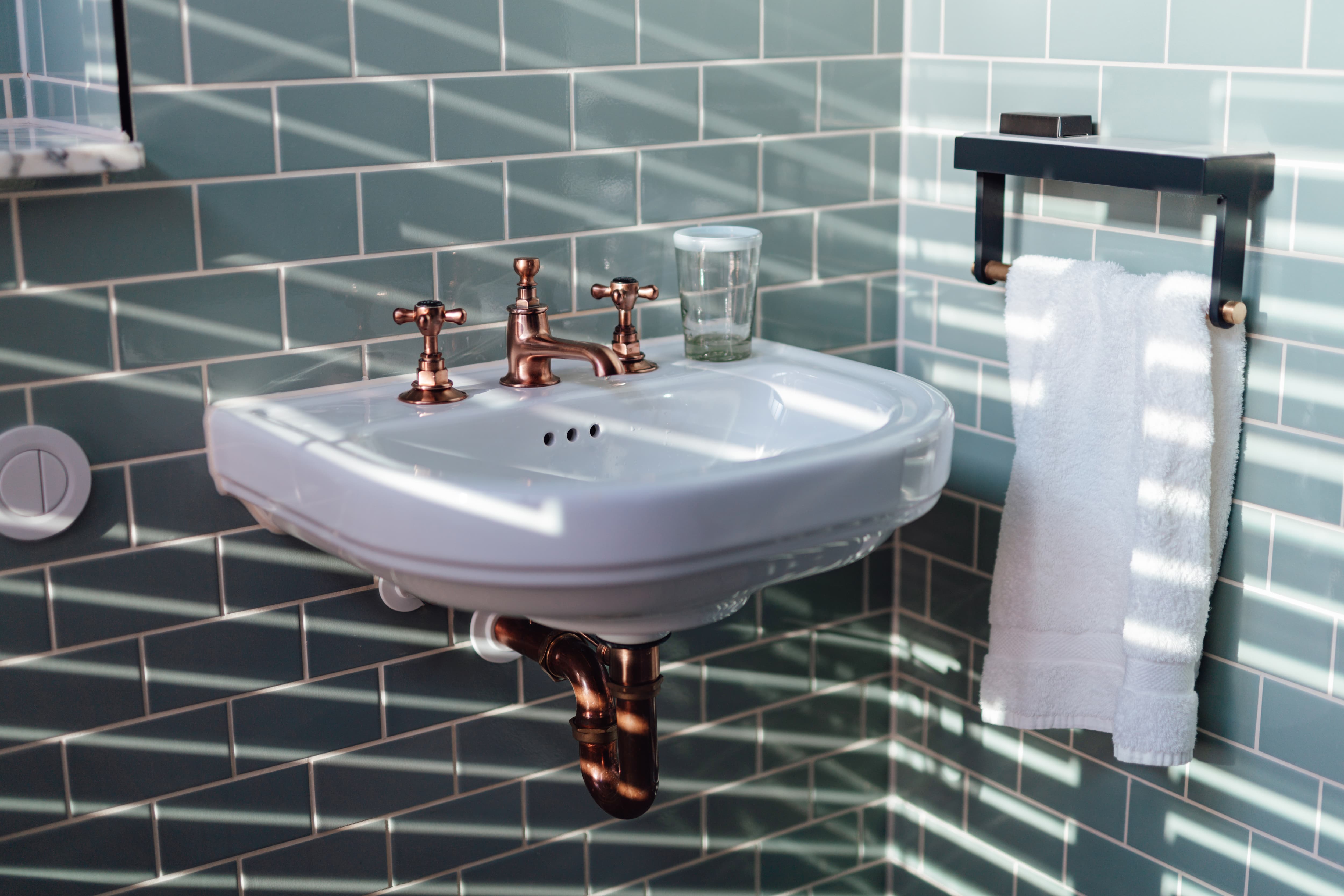 A sink with a brass faucet and pipes below