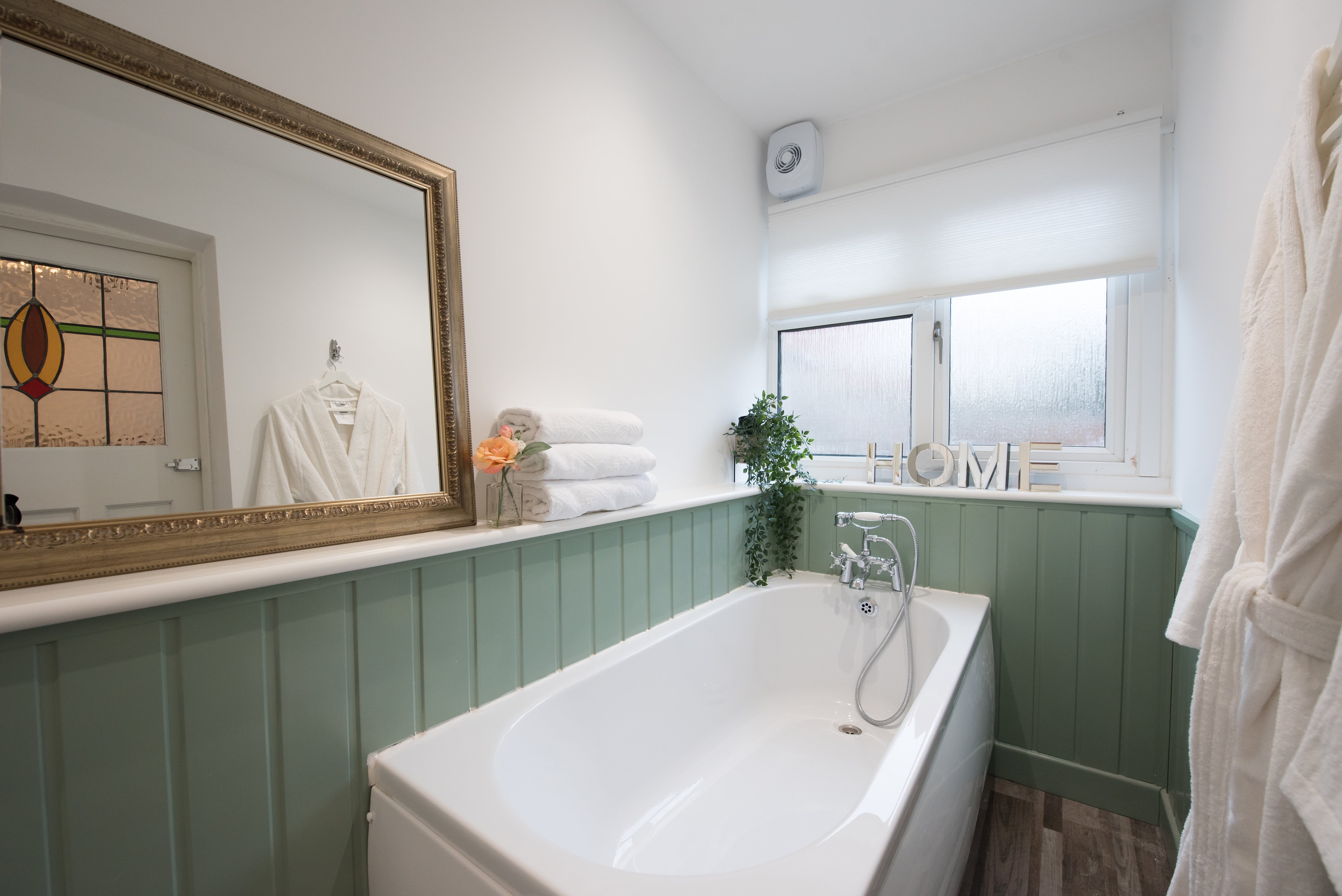 A light green colored wainscoting on a white bathroom wall
