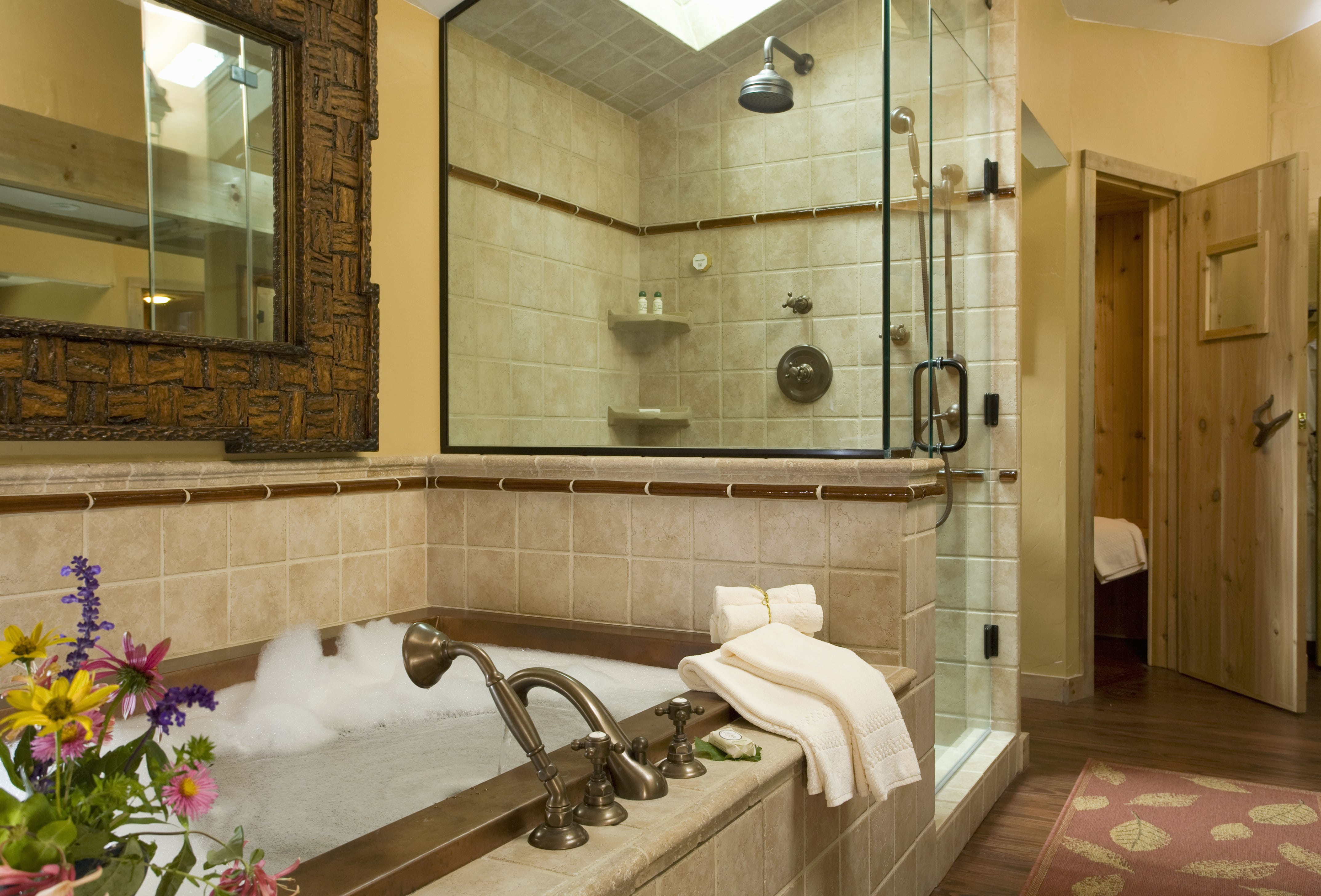 A large mirror with an intricate frame sits above a bathtub