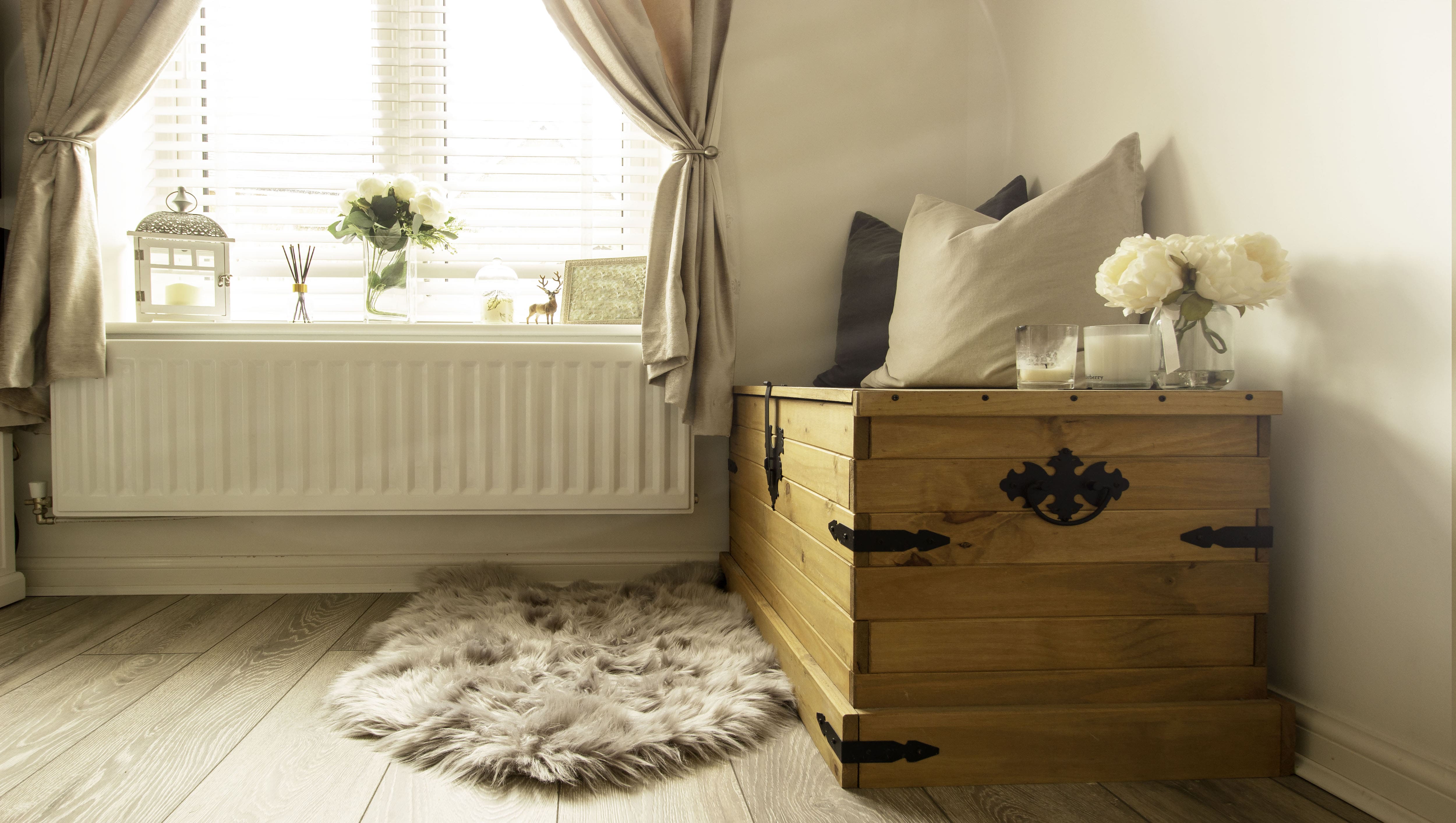 Antique wooden trunk as window seat in bedroom