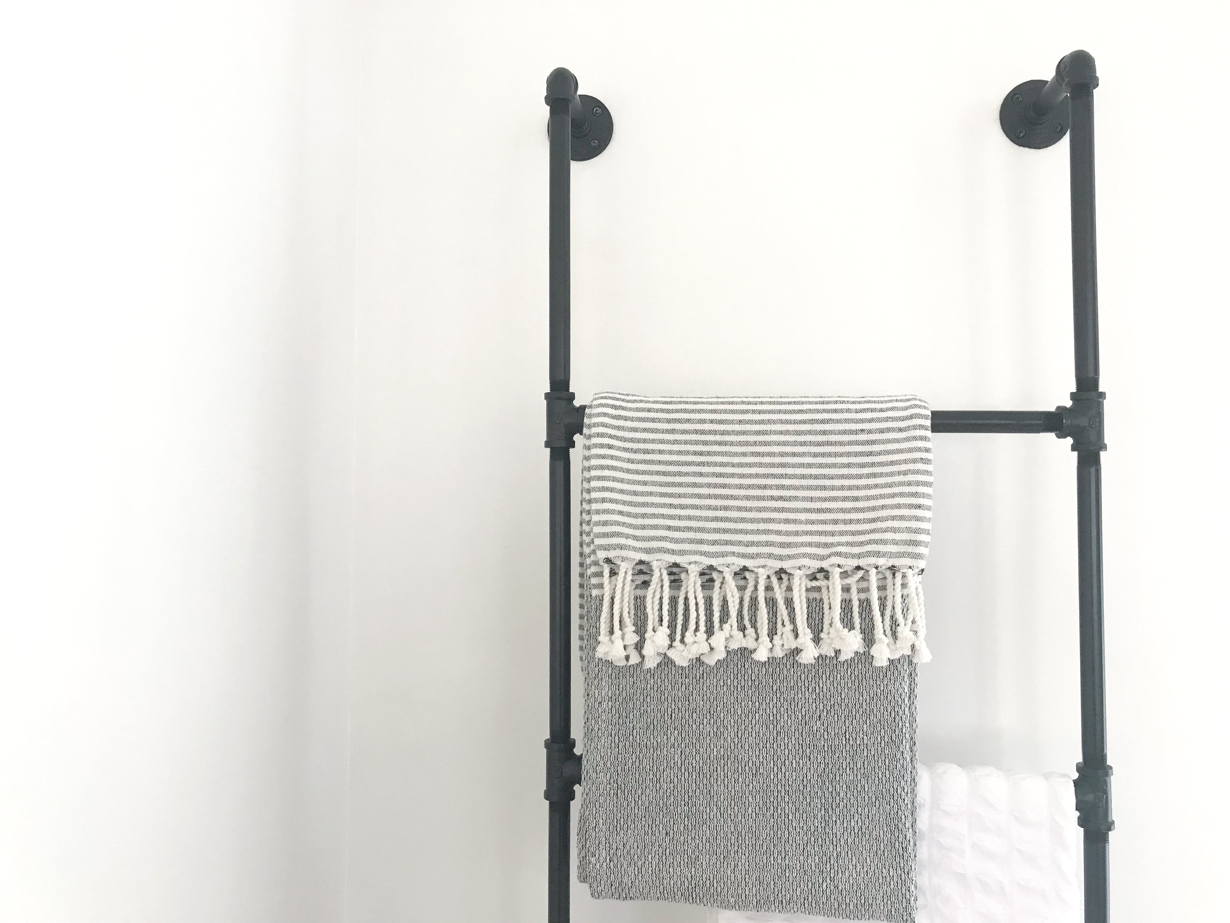 Metal blanket ladder with gray and white striped blanket