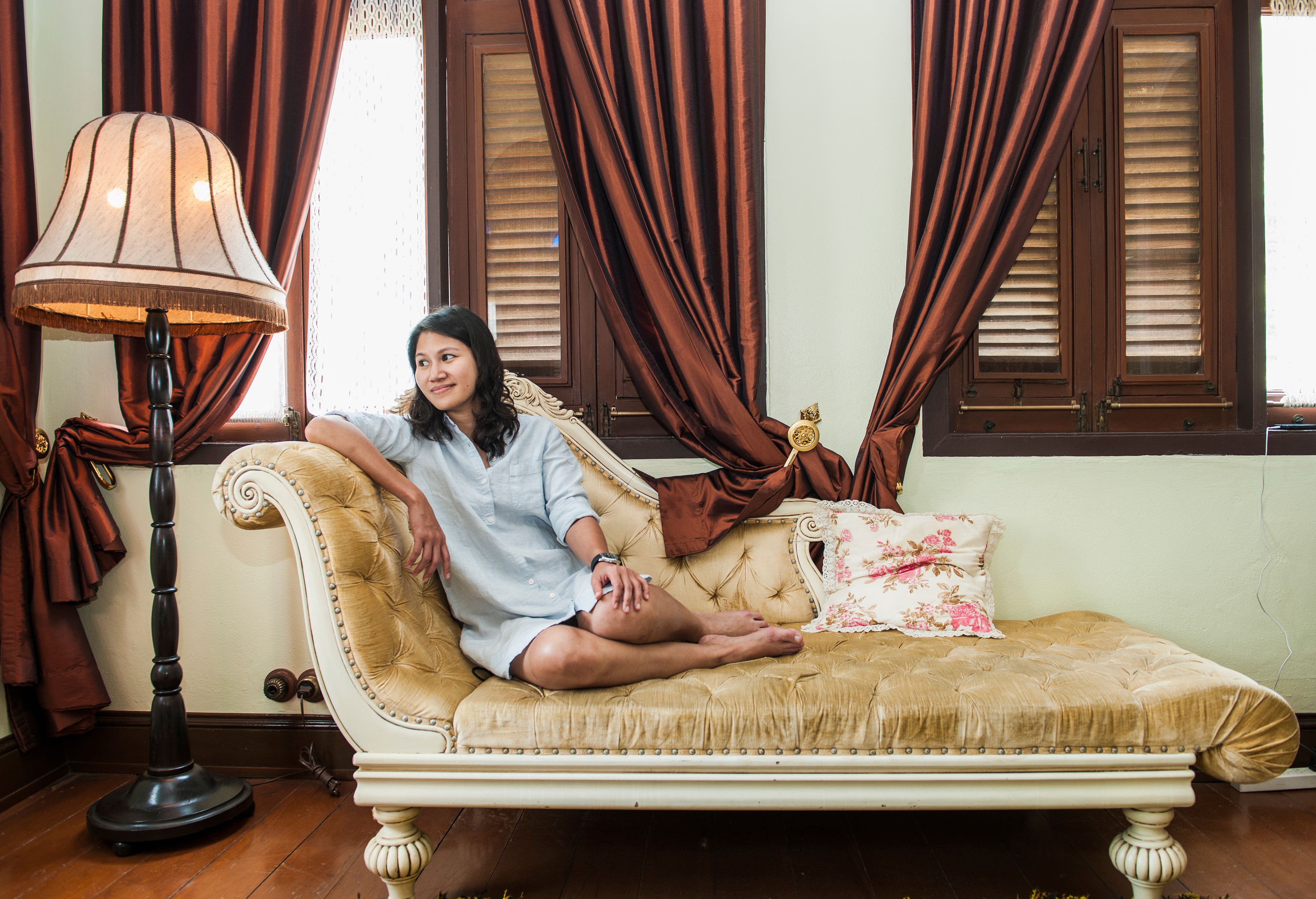 Woman relaxing on a chaise lounge in large bedroom