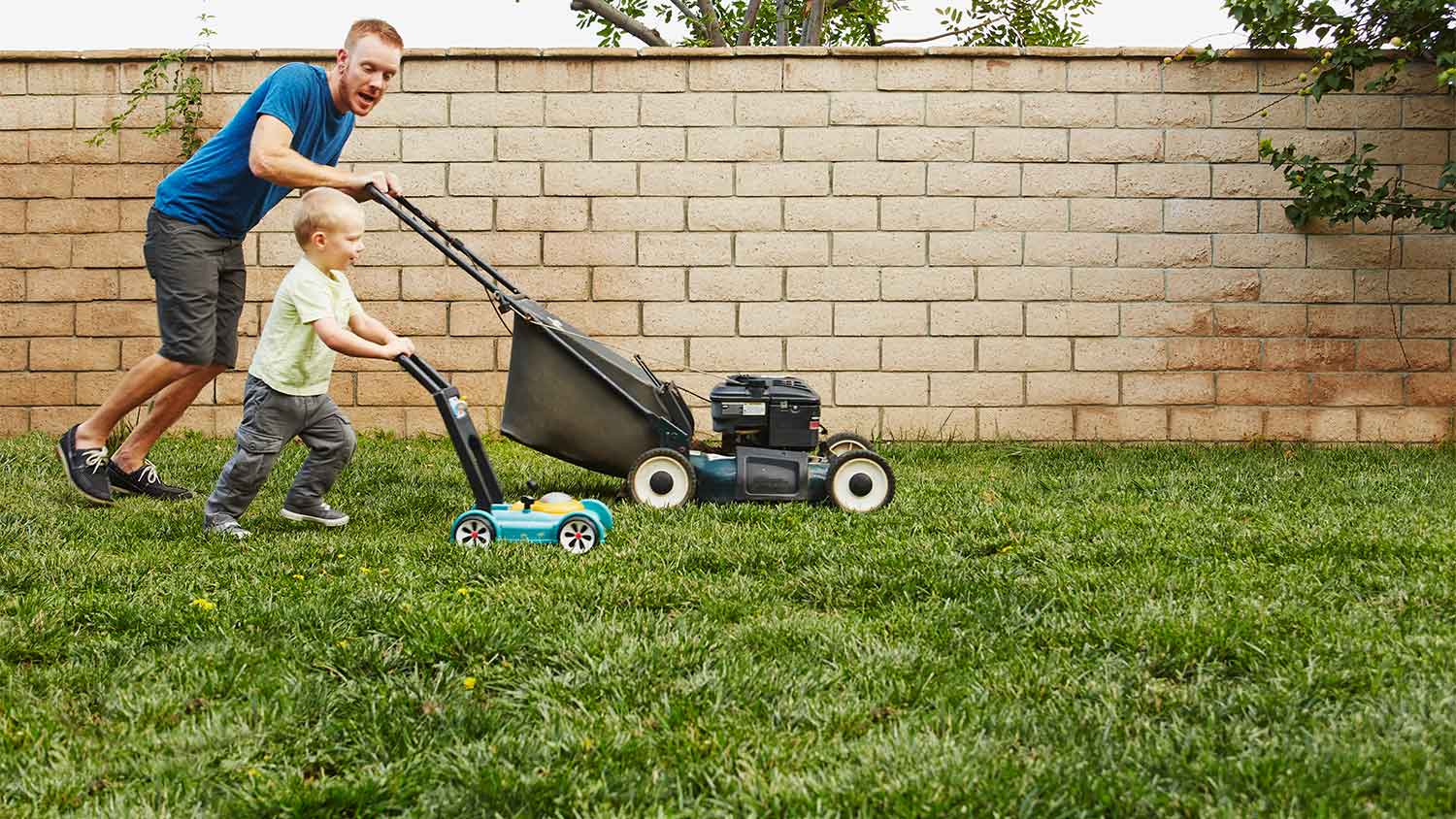 Father and son mowing lawn