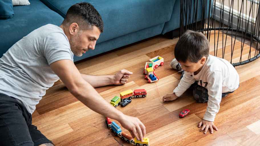 Father and son sitting on the floor and playing with toys