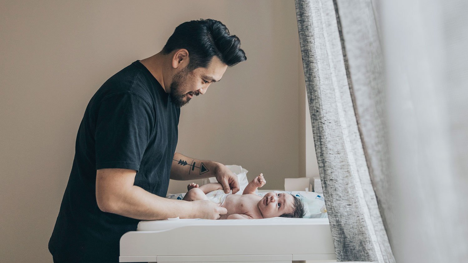 Father changing his baby diaper in the nursery room