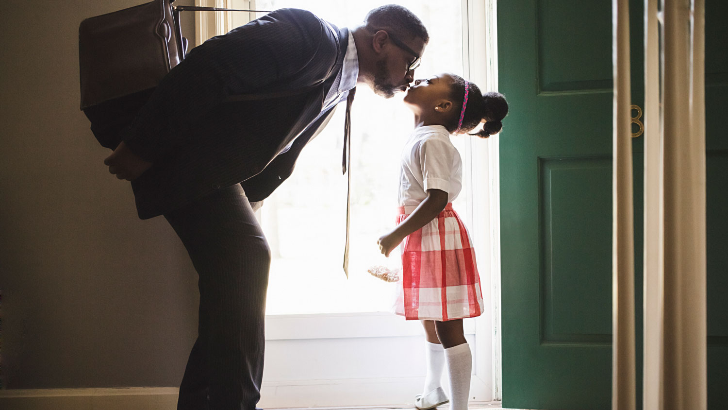 A father kissing his daughter as he leaves for work