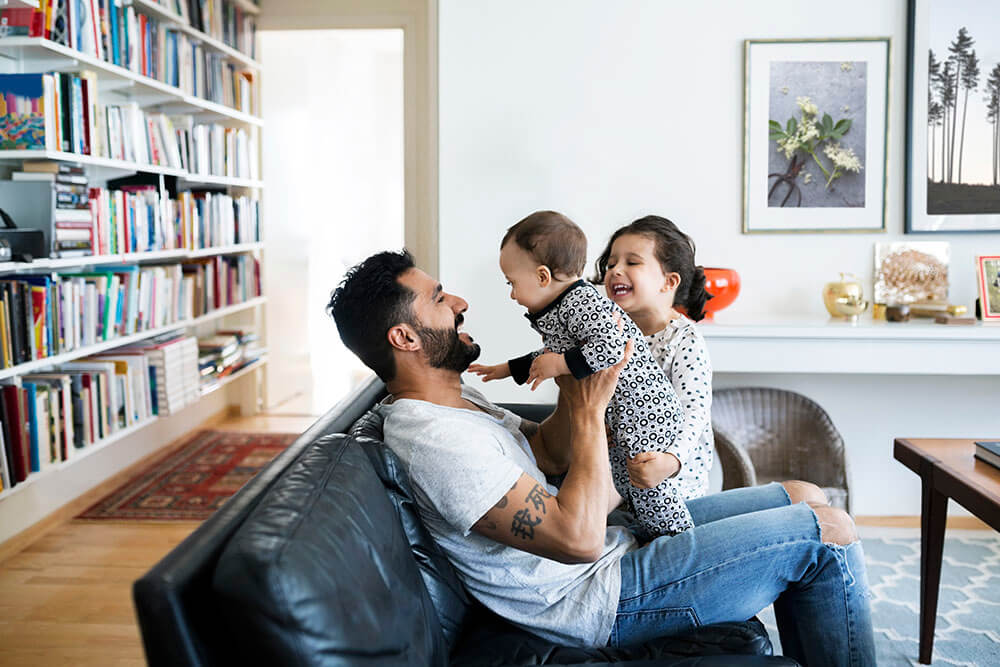 Father playing with children on couch