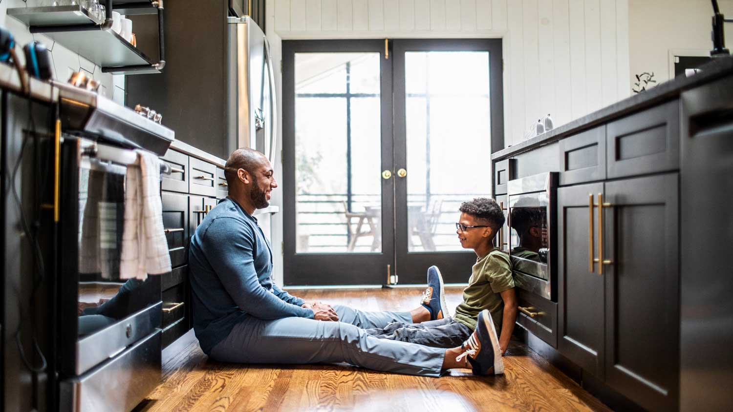 A father and his son sitting down in a galley kitchen