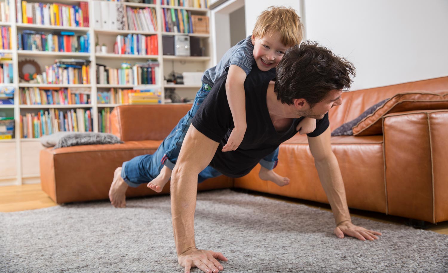 A father doing push ups with son on his back