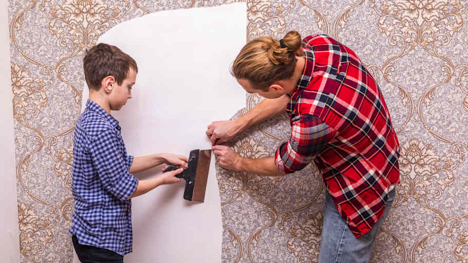 father and son peeling off wallpaper 