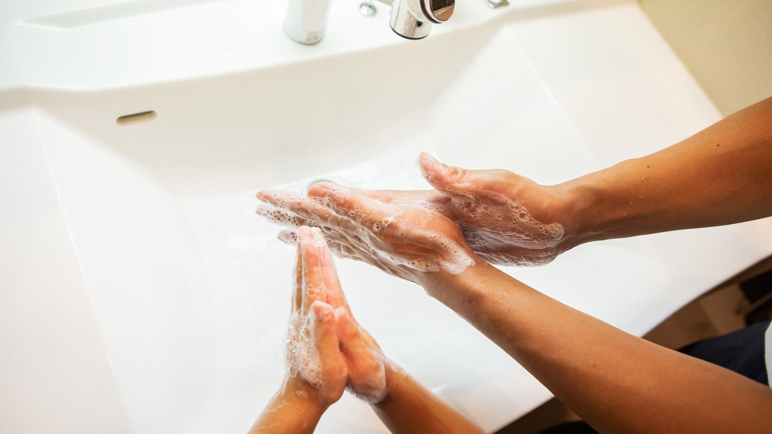 Top view of a father and son washing their hands in the sink