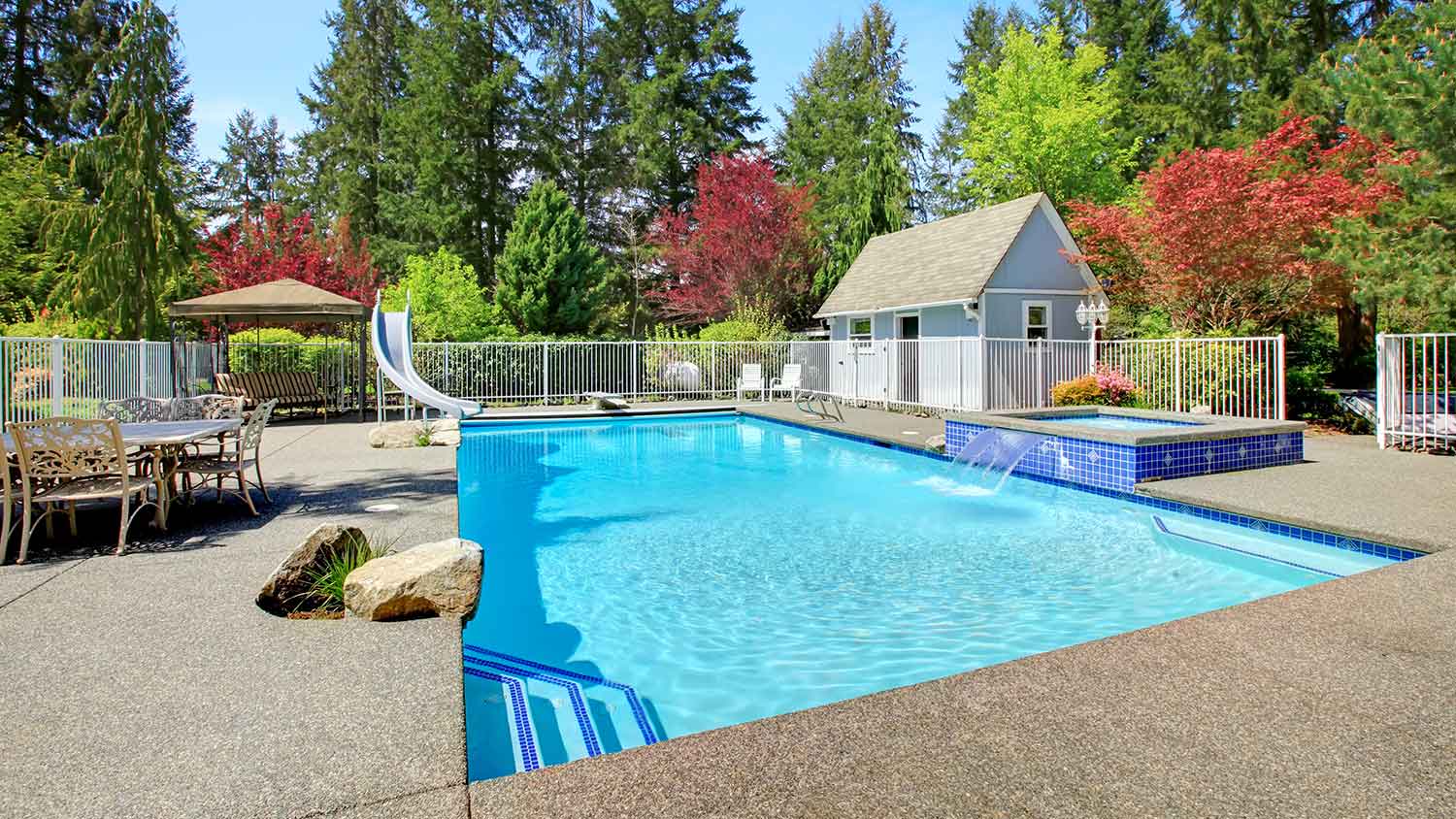 Fenced in swimming pool with small pool house