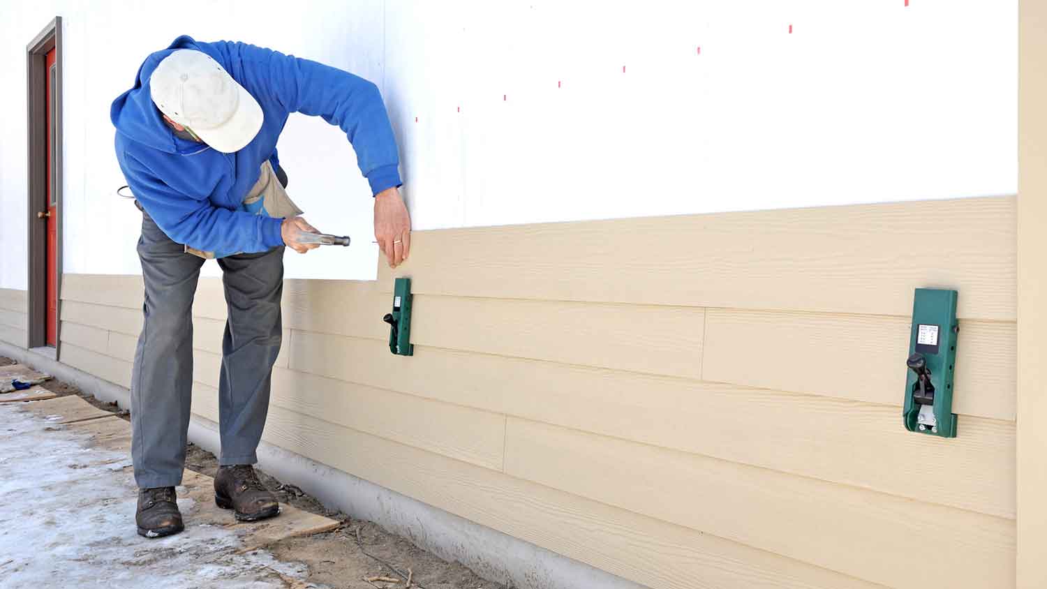 Woker installing fiber cement siding boards on the wall