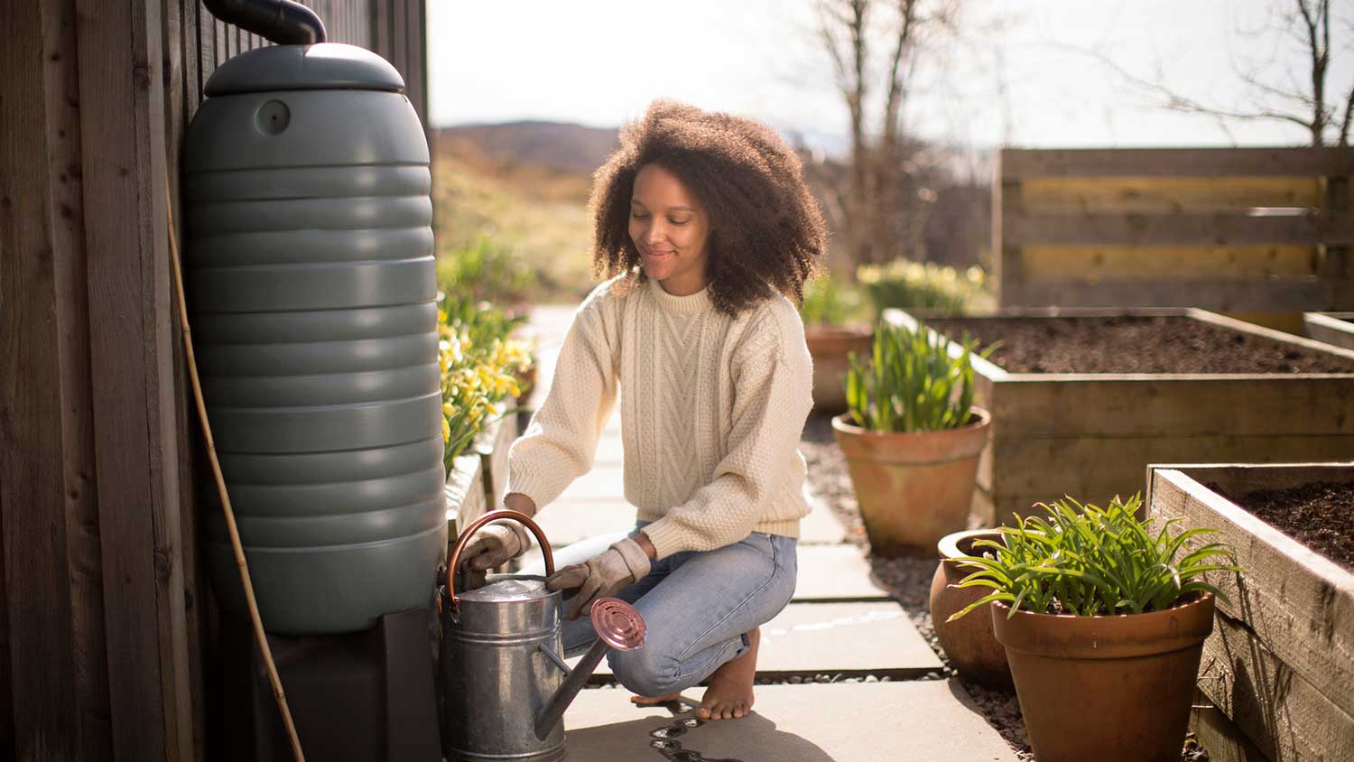 Woman using rain water to fill up watering can