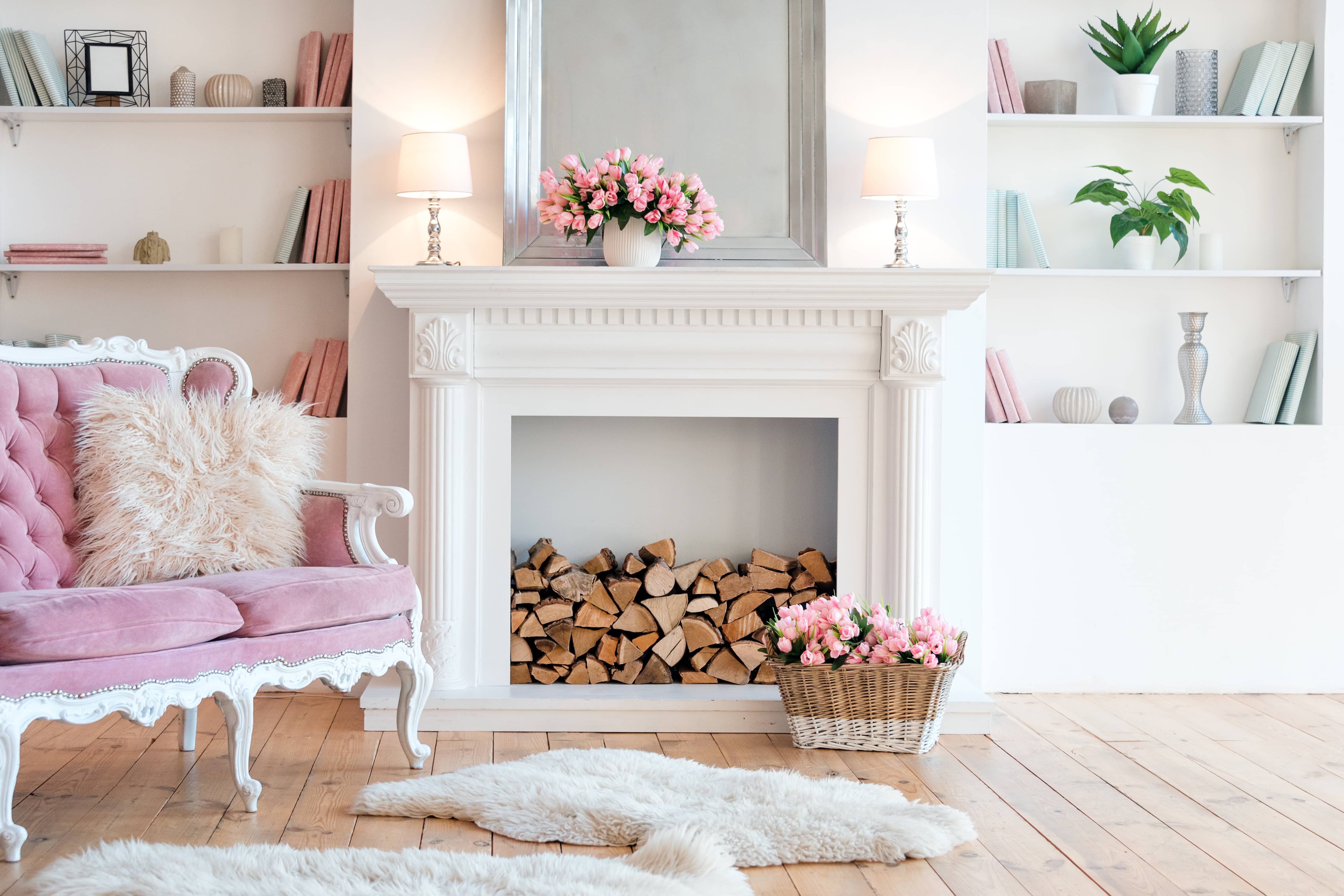 Living room with white fireplace, white built-ins, pink sofa, and pink tulips on the mantel and in a basket in front