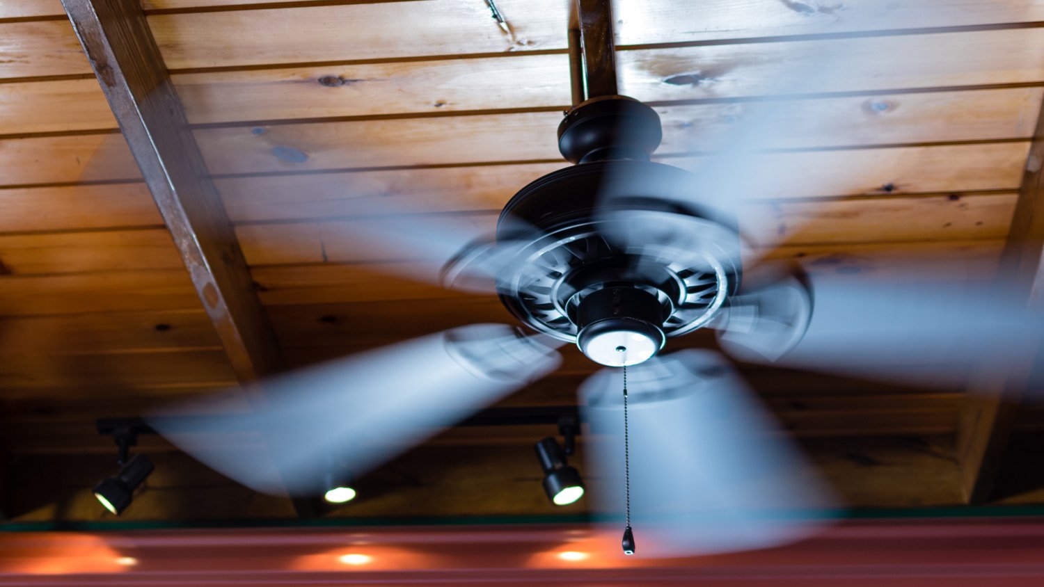 A ceiling fan shows motion blur as its blades spin around.