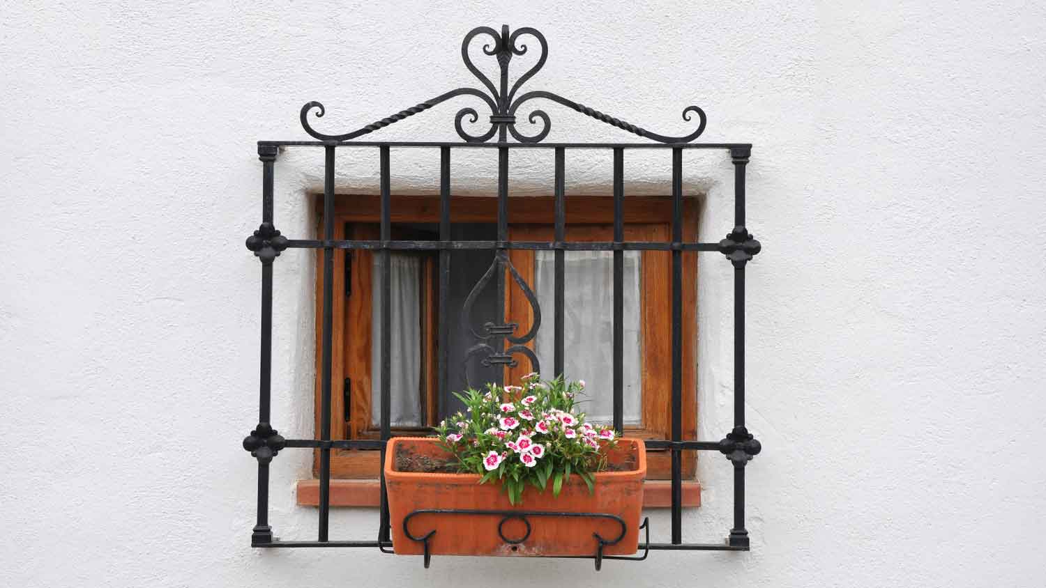 Small window with black steel bars on a white wall