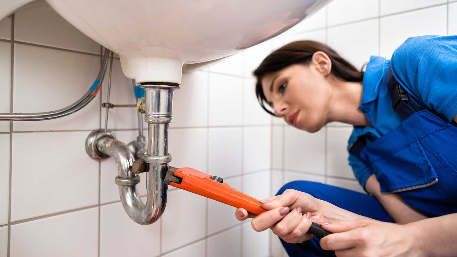 Woman fixing bathroom sink pipe