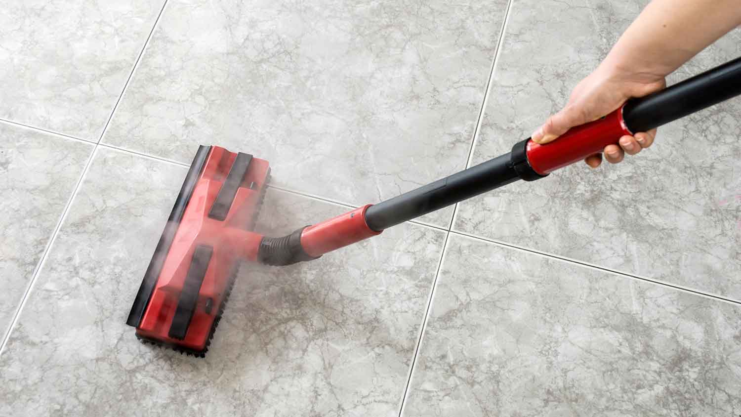 Person using steam mop to clean tile flooring