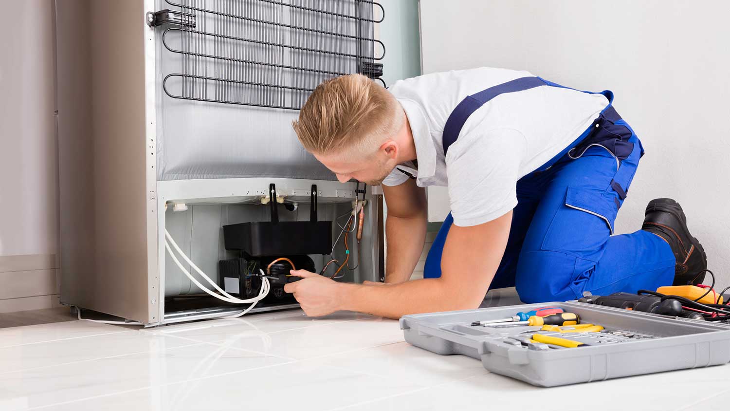 Technician inspecting the compressor of a refrigerator
