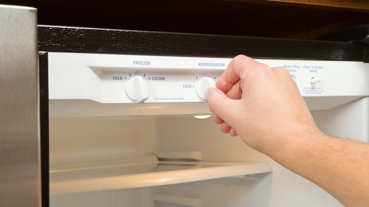 man adjusting thermostat in fridge