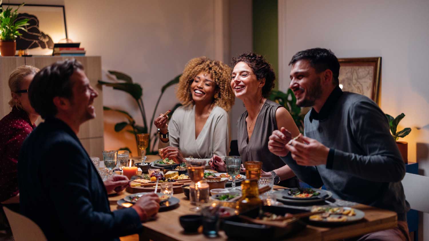 Friends talking and laughing while enjoying their dinner 