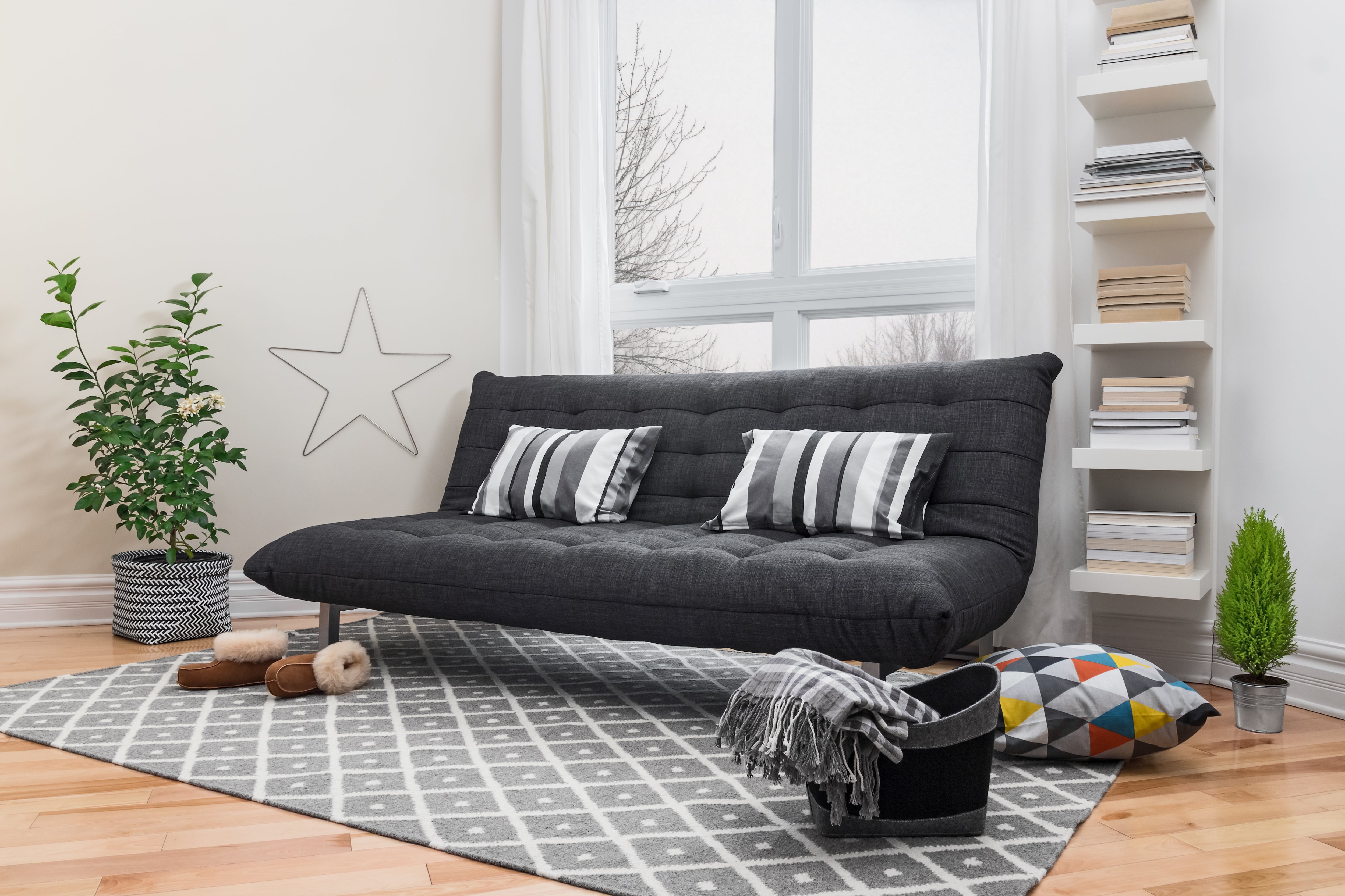 A grey futon in a bright room with white walls