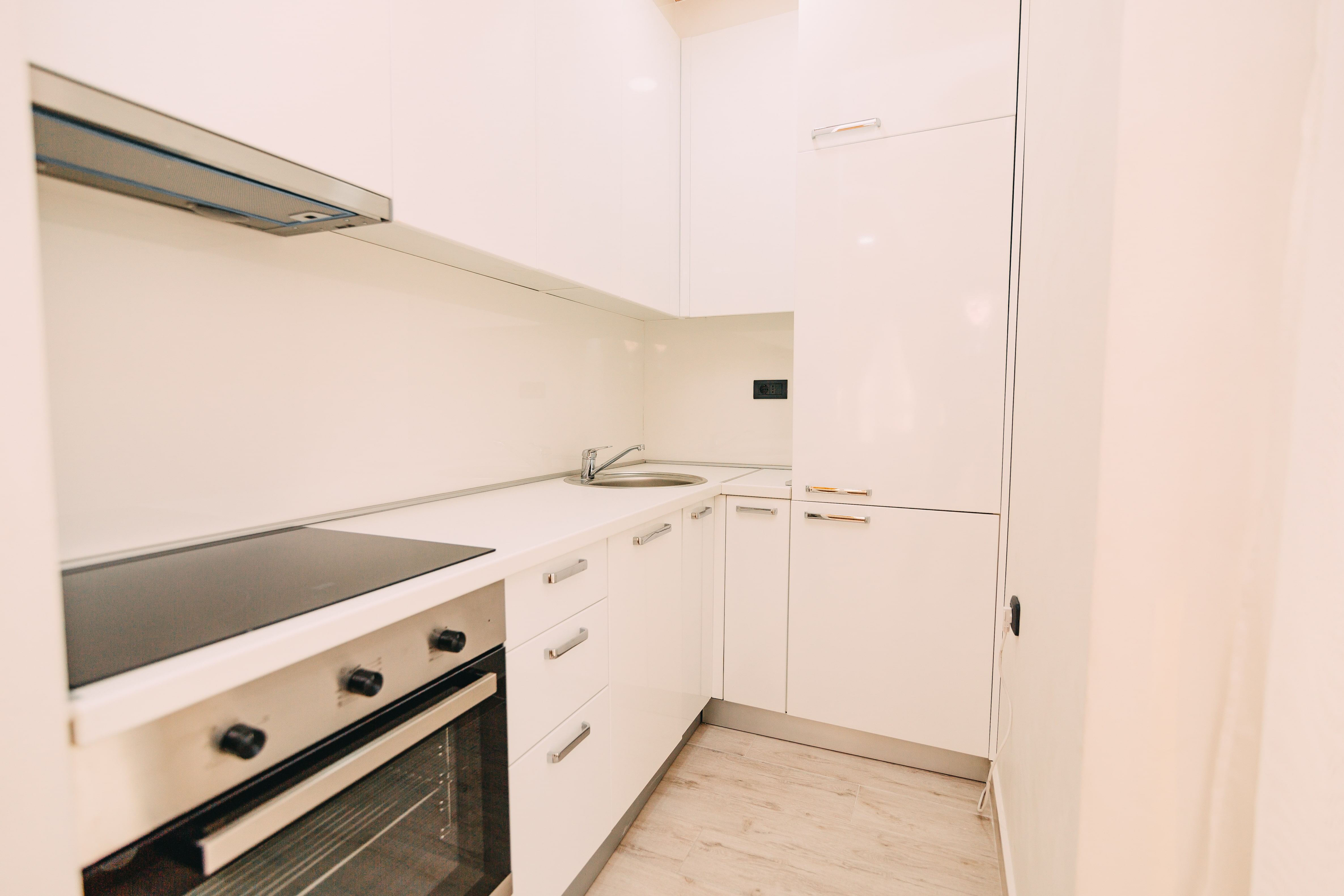 An all-white kitchenette with large floor-to-ceiling cabinets 