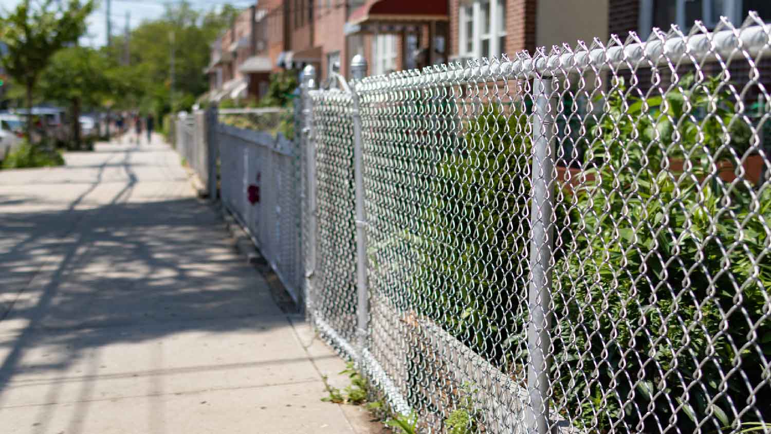 A galvanized chain link fence on a row of houses