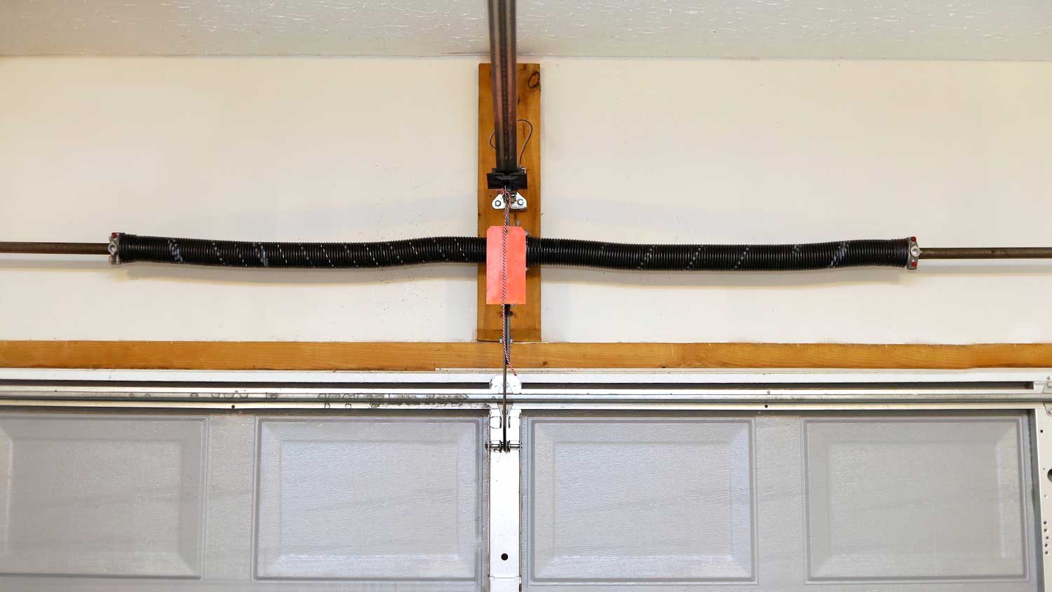 Early-set torsion springs mounted above garage door 