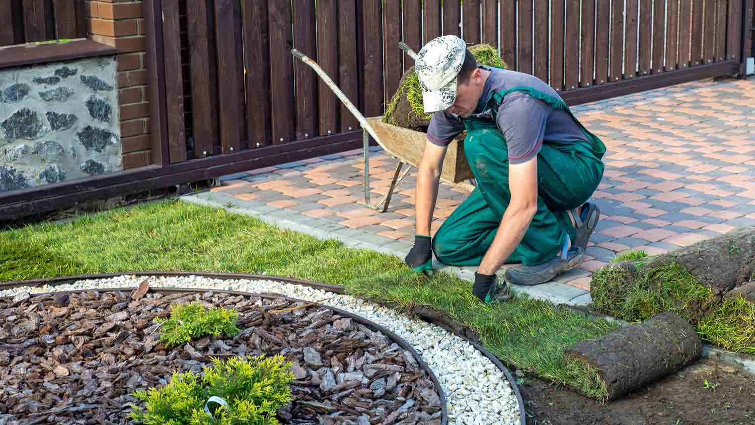 gardener applying turf in backyard