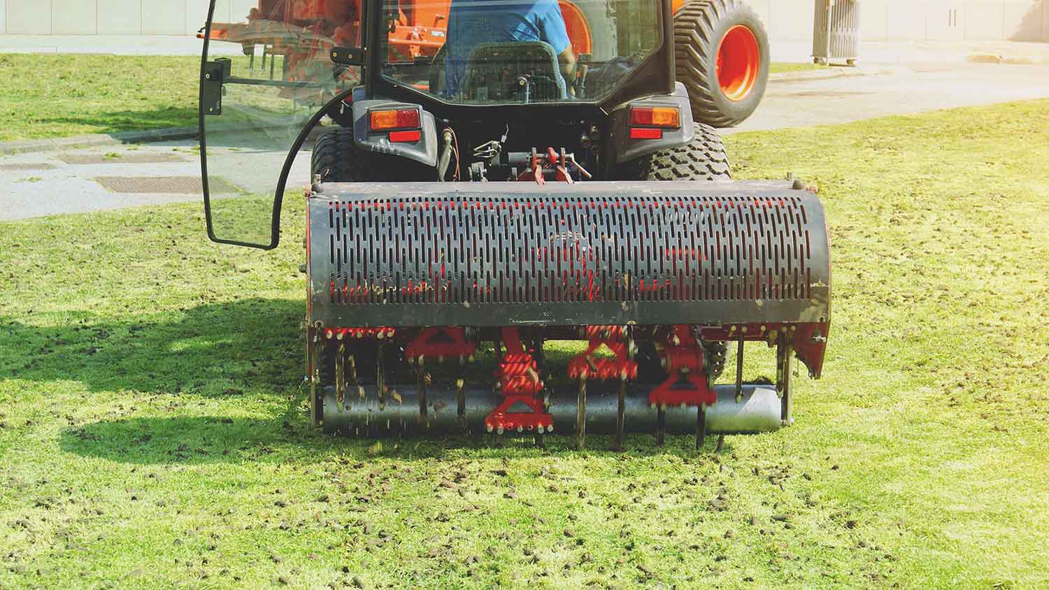 Gardener operating soil aeration machine in the yard