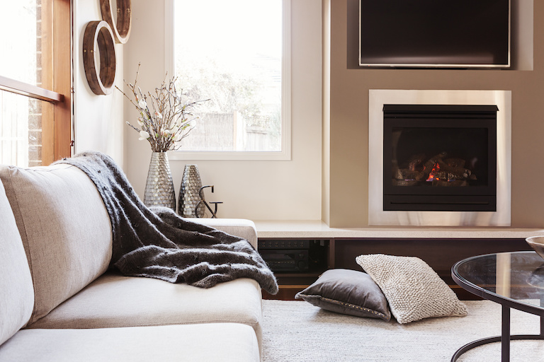 gas fireplace in living room with couch, blankets, pillows, and rug
