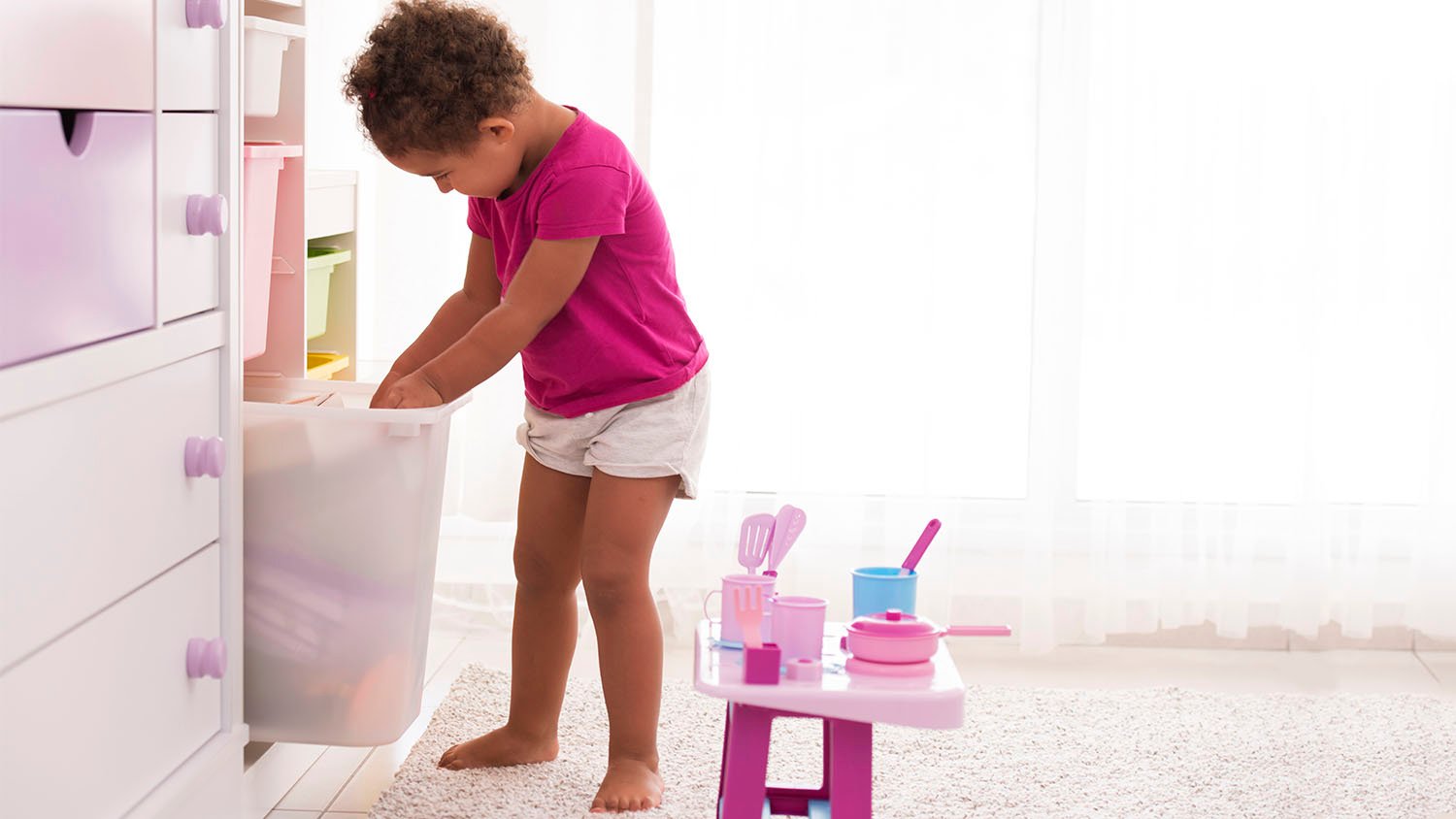 little girl getting toys out of bin