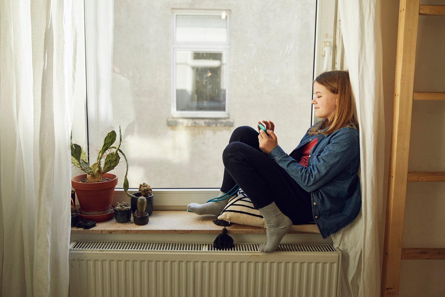 A girl sitting at the window next to the radiator