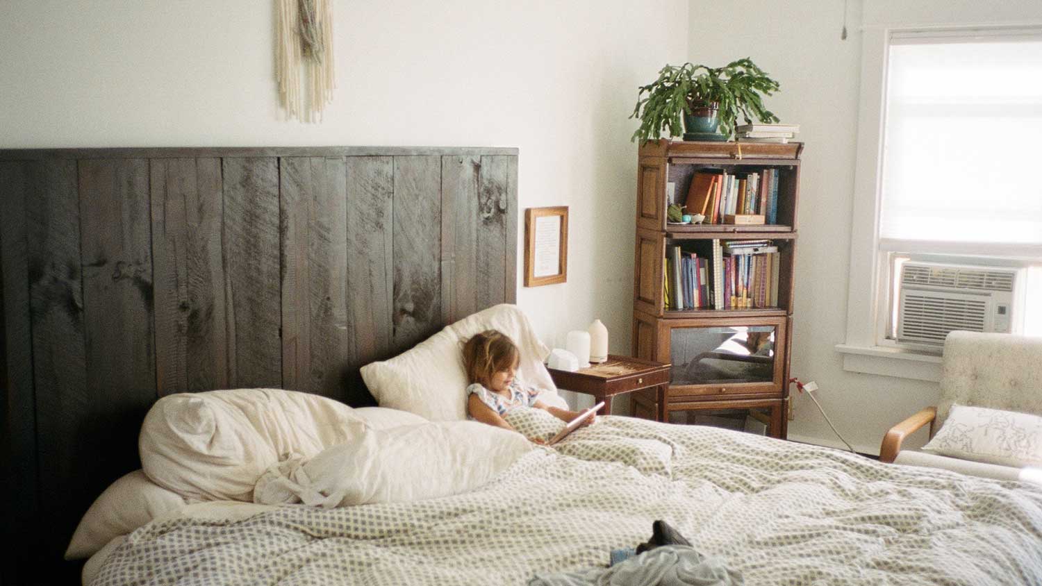 Little girl sitting in bed using her tablet