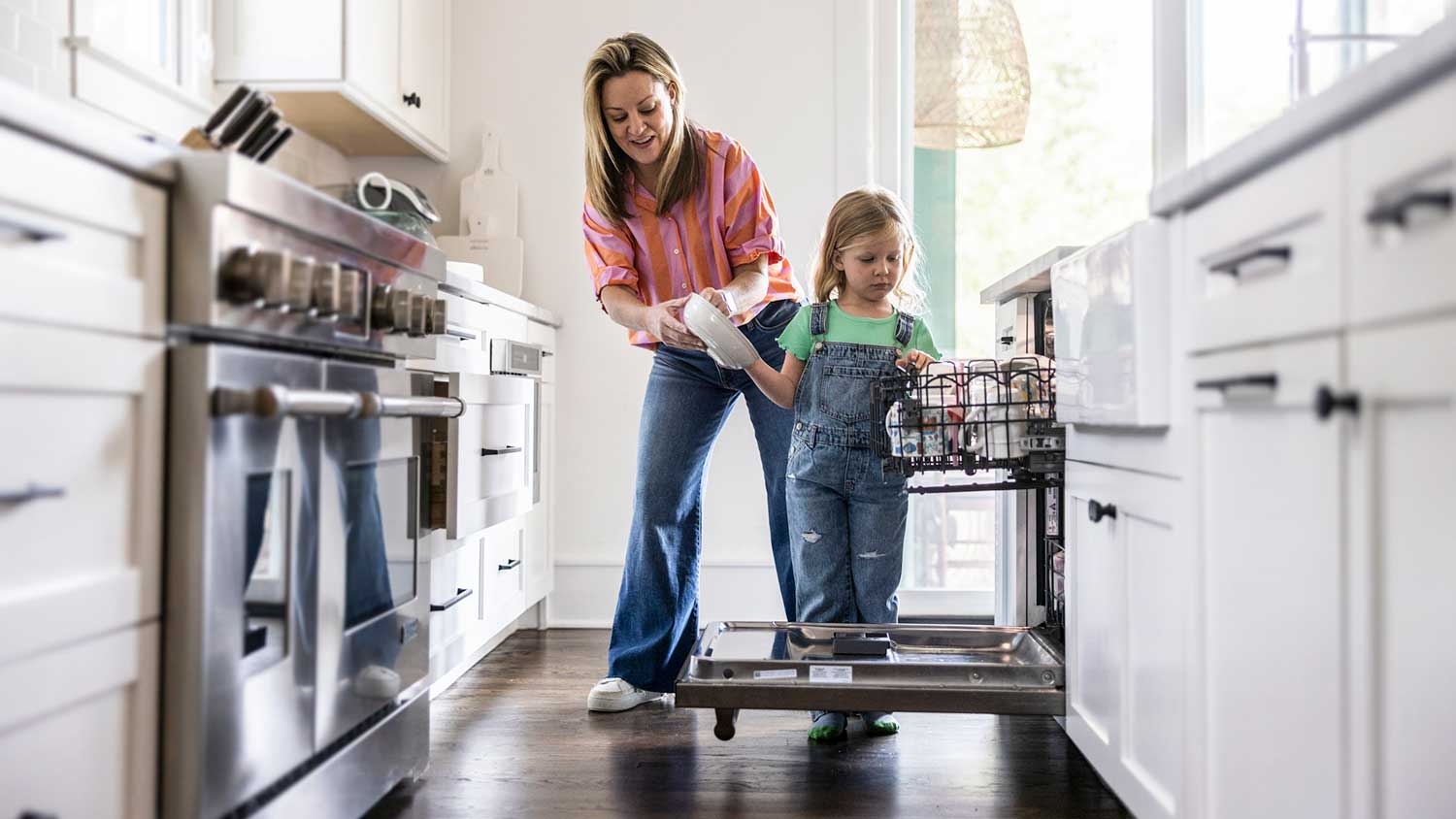 Mother and daughter putting clean dishes away