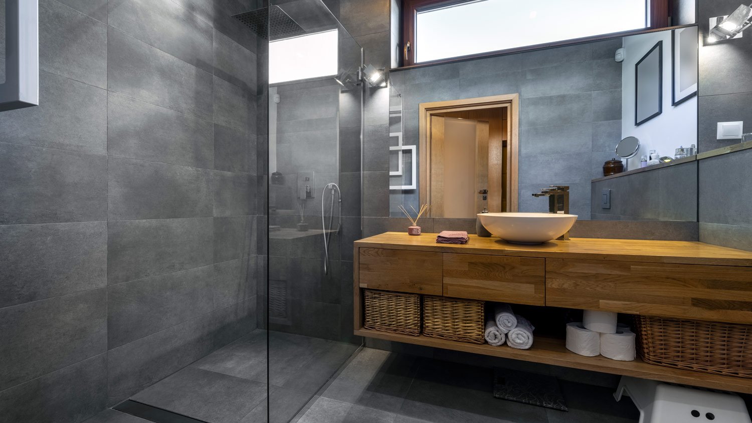 Modern bathroom in gray and wooden finishing with glass shower door