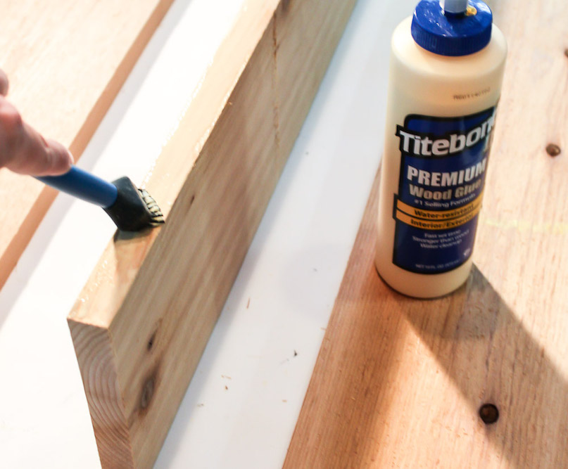 applying wood glue to side of wood board