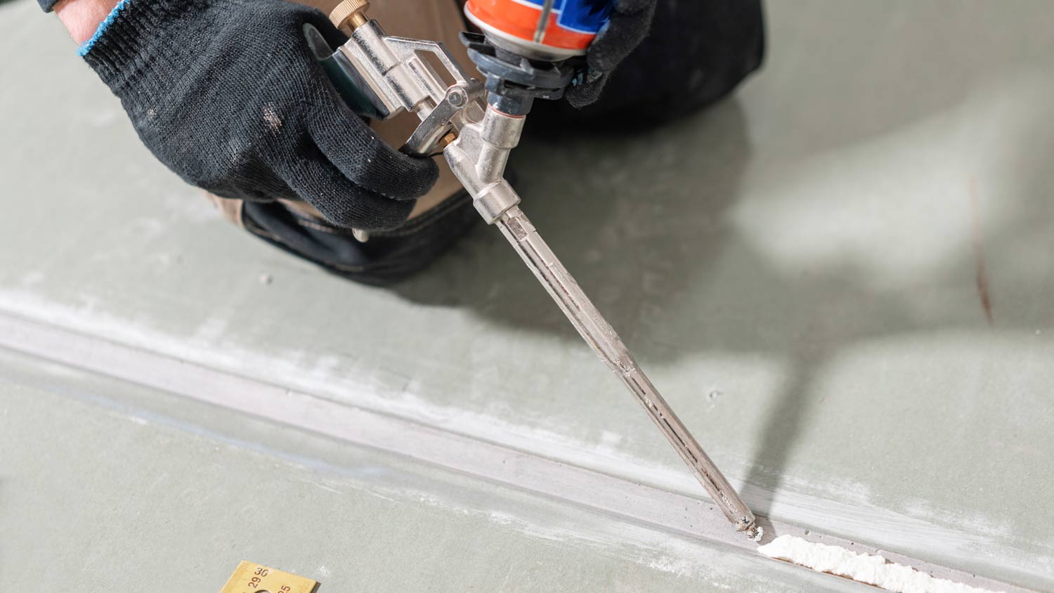 man holding glue gun applicator for drywall