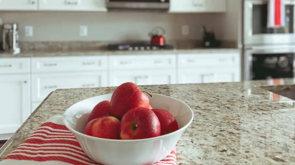 A bowl with apples on a kitchen granite countertop