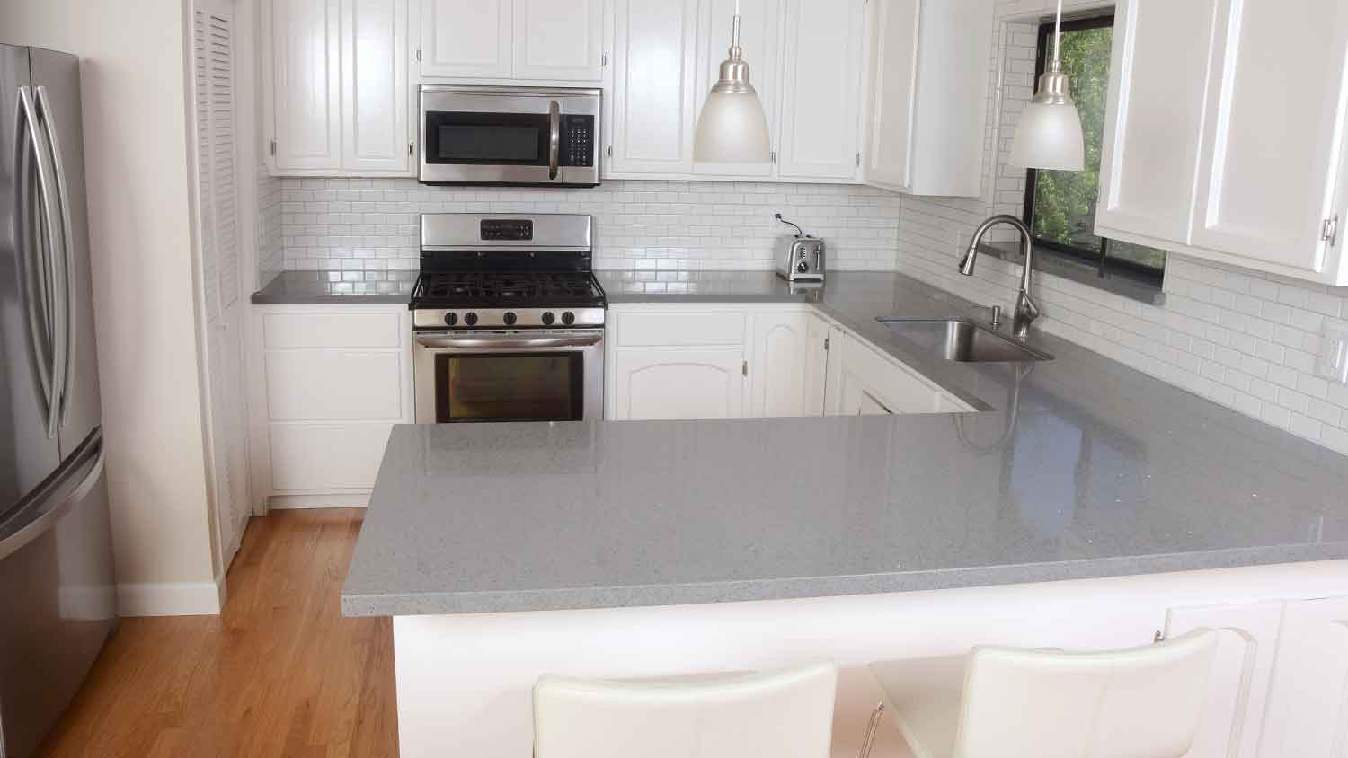 Kitchen with gray quartz countertops and white cabinets