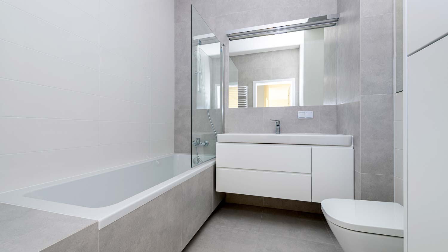 A gray and white minimal bathroom with a ceramic tiles bathtub