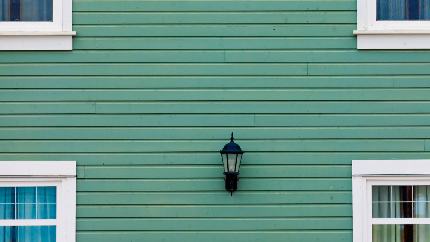 Green fiber cement siding with a black lamp on the exterior of a house