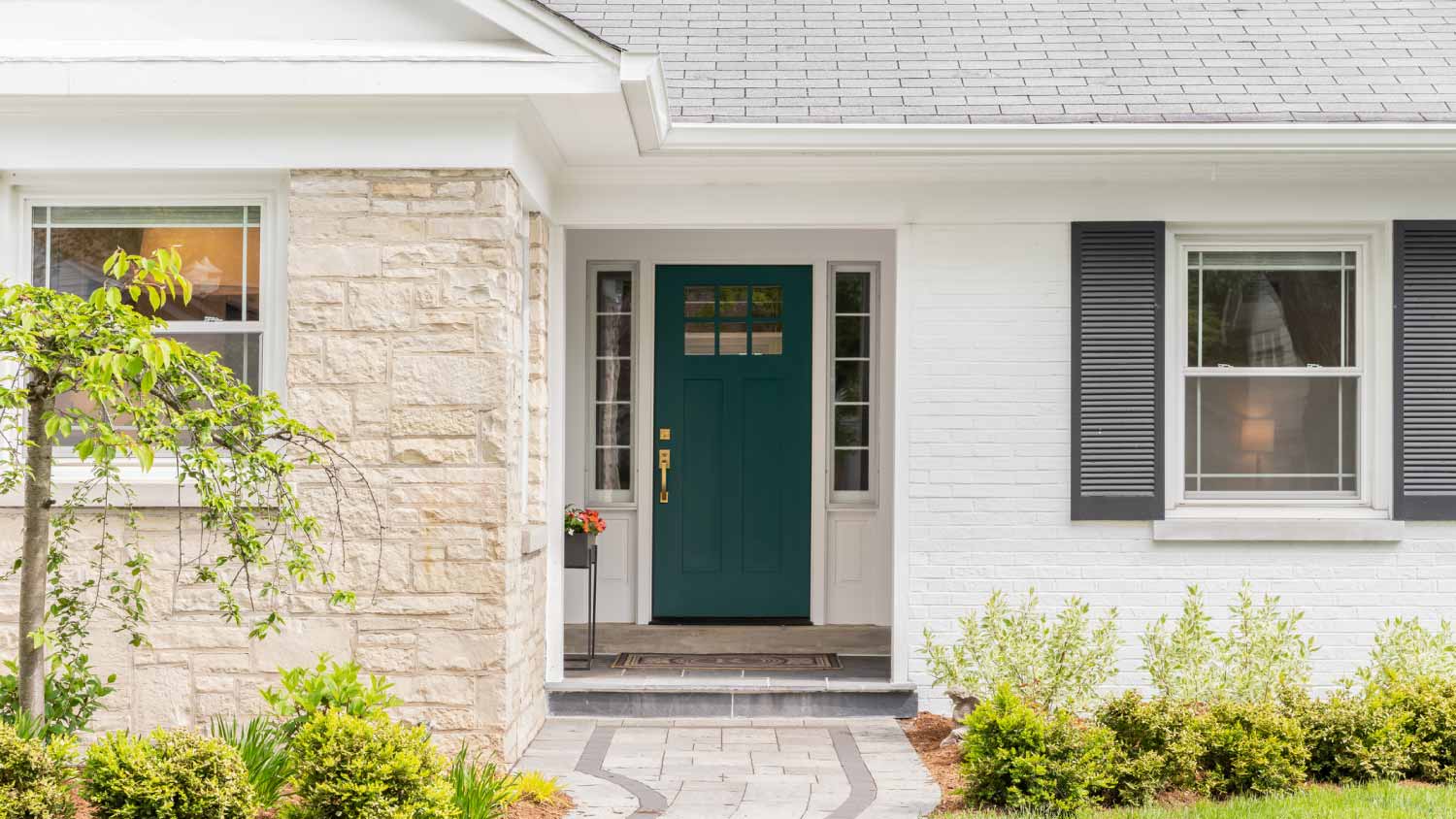 A green front door detail on a white home