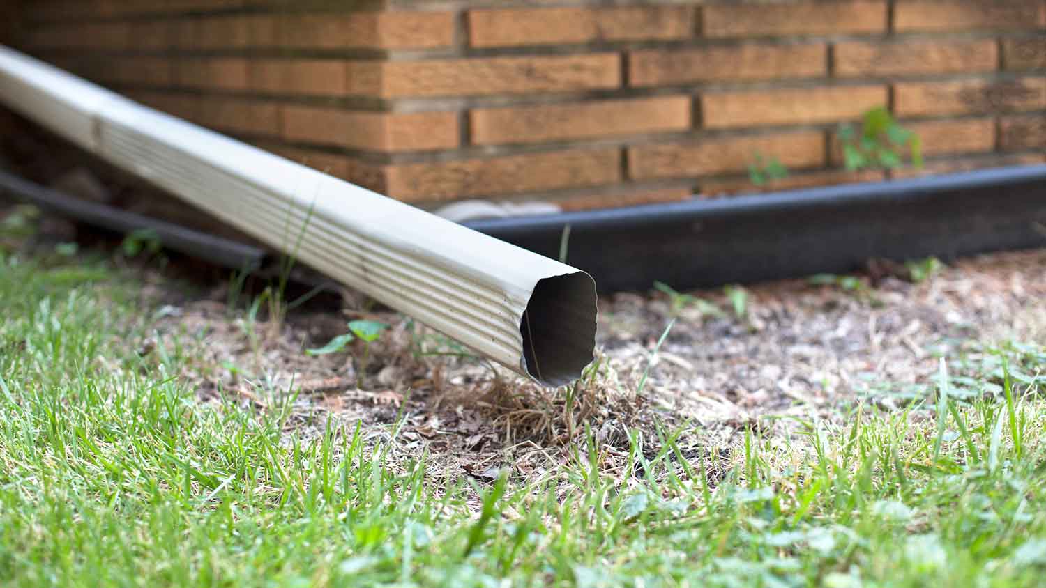 Gutter downspout extension installed on a brick house