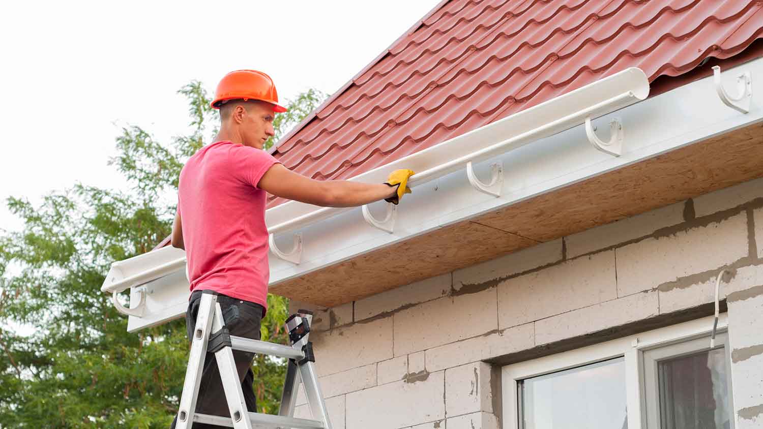 Roofer installing PVC gutters on a new house