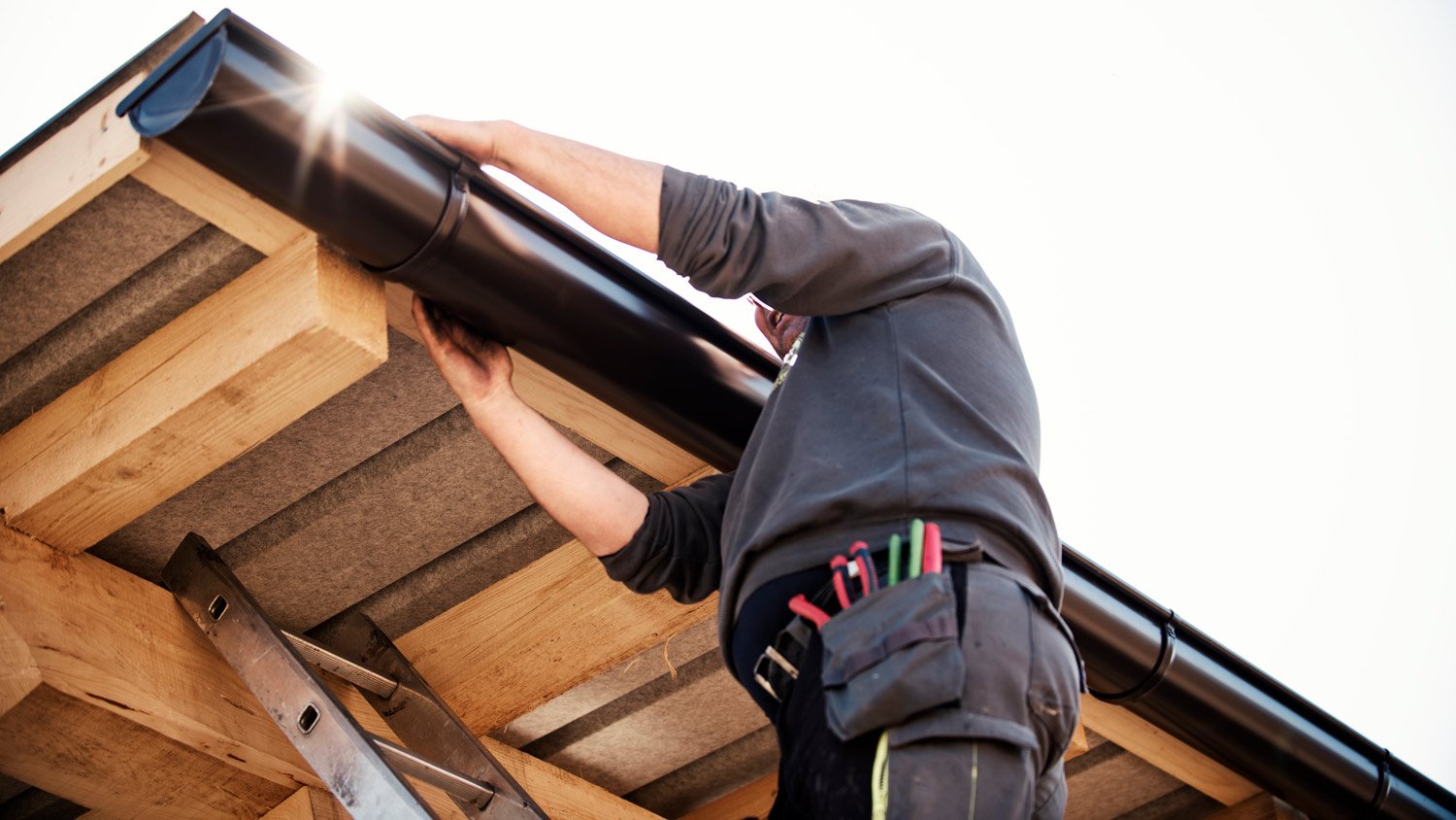 Worker on roof installing gutter